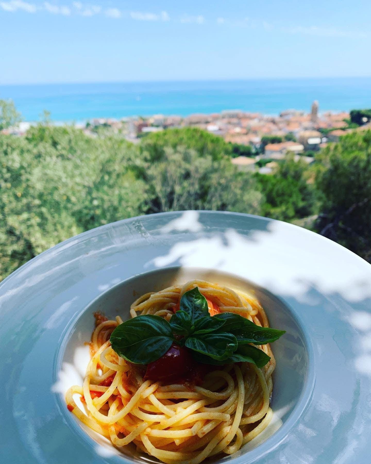 Tavola con specialita locali, calici di vino e vista sul mare